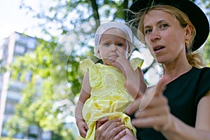 Horizontal photo of a young European blonde in a hat and with a small daughter in her arms