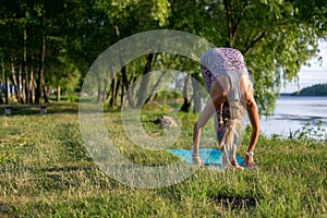 Horizontal photo of a young woman doing yoga on the background of beautiful countryside