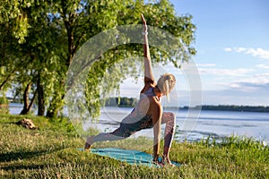 Horizontal photo of a young woman doing yoga on the background of beautiful summer nature
