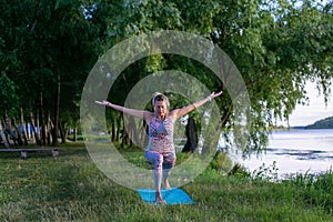 Horizontal photo of a young woman doing yoga on nature background