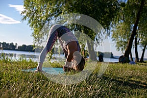 Horizontal photo of a young woman standing in an asana on a background of beautiful summer nature