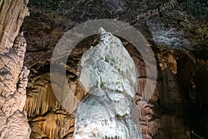 Horizontal picture of a giant white stalagmite inside Postojna cave.