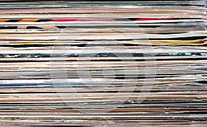 Horizontal pile of many close standing vinyl records covers as background front view closeup