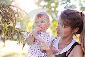 Horizontal portrait against the background of nature of a pretty twenty five year old woman with a one year old daughter in her