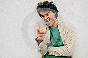 Horizontal portrait of cheerful young man with curly hair, smiling and looking up, feeling joyful, standing at modern metal