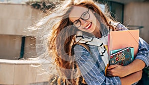 Horizontal portrait of a cheerful young student woman with red hair wearing transparent eyeglasses standing next to the college