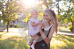 Horizontal portrait in the fresh air of a cute twenty five year old woman with a one year old daughter in her arms