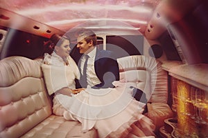 Horizontal portrait of lovely bride and fiance make fun in limousine