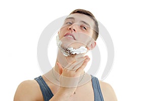 Horizontal portrait of a young handsome guy with foam on his face that shaves close your eyes