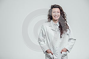 Horizontal portrait of a young pretty doctor`s girl. Smiling, looking straight into the camera. On a gray background