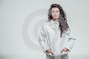 Horizontal portrait of a young pretty doctor`s girl. Smiling, looking straight into the camera. On a gray background