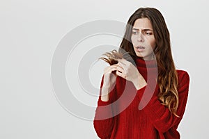 Horizontal portrait of young upset stunned woman in red sweater looking with sad expression of face at her dark long