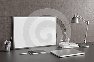 Horizontal poster frame mockup on the black table of home studio workspace with concrete wall. Side view, clipping path around