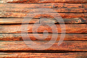 Horizontal red brown wood log outer wall of an aging log cabin for texture background