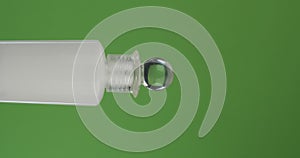 Horizontal rotation of a face cream bottle on a green screen. Close-up.