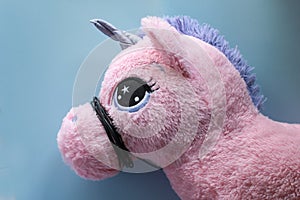 Horizontal selective focus shot of a pink unicorn soft toy, with wire around its mouth.Concept photo