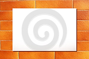 Horizontal sheet of clean white paper on a yellow-orange brick wall.