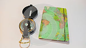 Horizontal shot of an antique compass and travel notebook on a white background