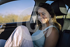Horizontal shot of a beautiful young caucasian female posing in the front seat of a car in a field