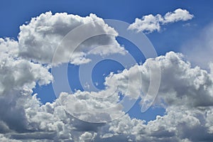 Horizontal shot of a bright blue sky with white puffy clouds.