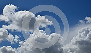 Horizontal shot of a bright blue sky with white puffy clouds.