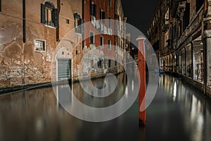 Horizontal shot of a canal between the old buildings in Venice, Italy during nighttime