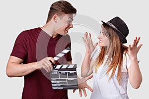 Horizontal shot of cheerful woman and man look positively at each other, gesture actively, have hesitant expressions, holds