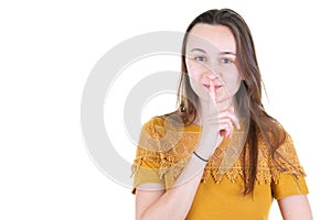 Horizontal shot of cute lovely young woman keeps fore finger on lips