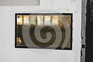 Horizontal shot of a empty brass plate on white brick wall