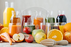 Horizontal shot of fresh fruit and vegetables on white table, glass jars of juice and orange squeezer. Healthy drinks concept.