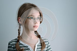 Horizontal shot of a Girl teenager with glasses and two braids. Portrait of the blonde girl