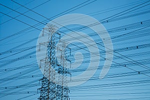 Horizontal shot of High-voltage towers silhouetted against blue