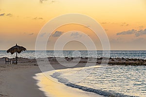 Horizontal shot of the mesmerizing view of the beach and sea, with umbrella and chairs at sunset