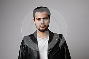 Horizontal shot of modern stylish young hipster man in a leather biker jacket posing over a white background. Isolated.