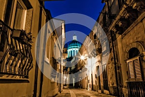 Horizontal shot of a narrow street in a nice neighborhood and a dome of a church at night