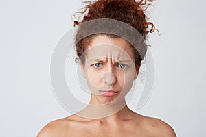 Horizontal shot of pensive confused young woman with curly hair and healthy skin standing half and looks worried