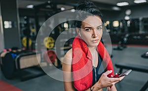 Horizontal shot portrait of a beautiful athlete young woman listening to music from her smartphone, having a break after workout