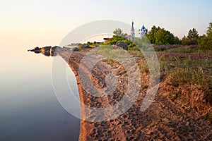 The shore of lake Peipus at sunset. Church of the apostles Peter and Paul in Vetvenik, Pskov region.