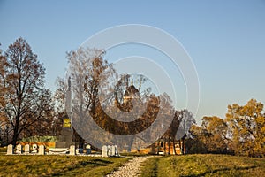 Horizontal shot of a stone monument in Borodino field, Russia with a church visible behind trees