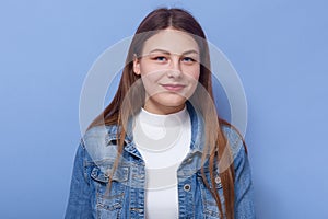 Horizontal shot of tender sweet attractive young female wearing white sweater and jeans jacket, having long fair hair, looking