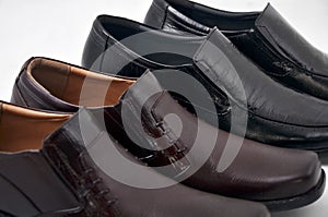 Horizontal shot of two pairs dark brown and black male shoes on a white background