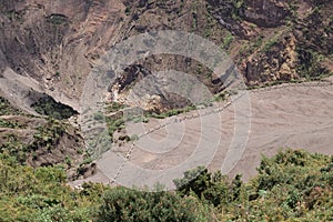 Horizontal shot of the viewpoint to the main crater surrounded with little vegetation rocky and sandy terrain with blue sky in the