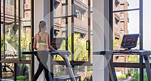 Horizontal shot of woman jogging on treadmill at health sport club at luxury resort. Female working out at a gym running