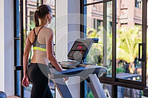 Horizontal shot of woman jogging on treadmill at health sport club at luxury resort. Female working out at a gym running