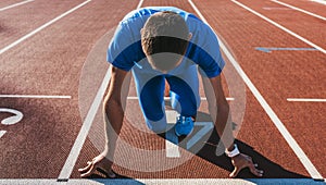 Horizontal shot of young male athlete at starting block on running track. Caucasian sprinter man in starting position for running
