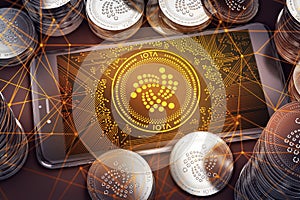 Horizontal smartphone with IOTA on-screen among piles of IOTA coins. IOTA in danger concept.