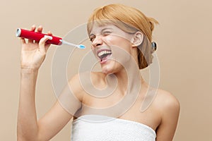 Horizontal studio shot.A joyful woman in a towel with clean, beautiful, well-groomed skin, short red hair on a beige