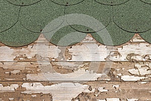 Horizontal texture of a green shingles roof and old brown boards painted with impregnation for wood