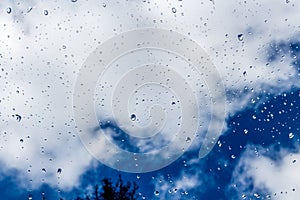 A horizontal texture of water droplets is on the glass and on a background of blue sky