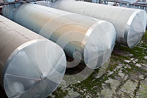 Horizontal three storage tanks storage barrels of chemical plant surrounded by pipeline valves and ladders